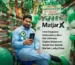 A shop owner sitting inside a Zainab Market shop decorated with Pakistani flags and balloons for Independence Day, holding a phone with the MatjarX logo and title text displayed beside him.